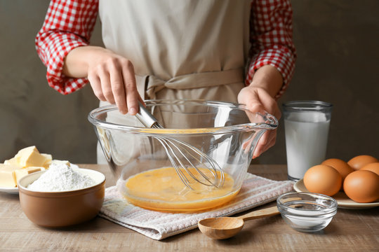 Woman making dough for a pie in bowl on table