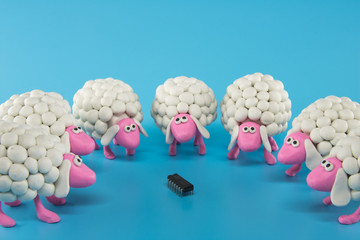 White polymer clay sheep gather around an electronic chip on a blue background