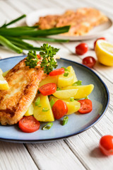Fried fish fillets in batter, served with potato, tomato and scallion