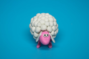 A single white polymer clay cute sheep on a blue solid background