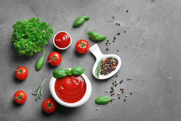 Delicious ketchup in bowl with ingredients on dark background, top view