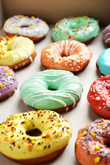 Tasty donuts with sprinkles on paper background