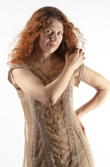 Portrait of a beautiful young red curly girl with bright make-up in a gold dress
