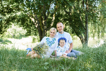 Happy young family with daughter spending time together outside in green nature.