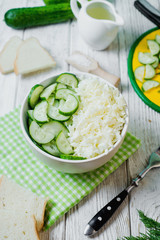  vegetarian Healthy food, light, low calorie fitness salad of fresh cucumbers, cabbage and dill with olive or sunflower oil, spices and salt on a light wooden background 