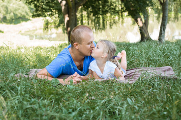 Naklejka na ściany i meble portrait if father kissing daughter in outdoor against nature background, ukrainian man kissing his daughter.