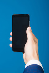 hand with mobile phone on blue background