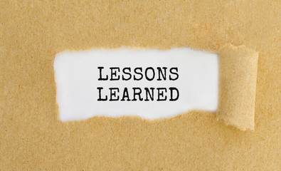 Text LESSONS LEARNED appearing behind ripped brown paper