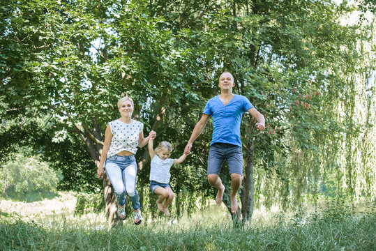 Rear View Of Joyful Happy Family Jumping Together At Outdoor Park