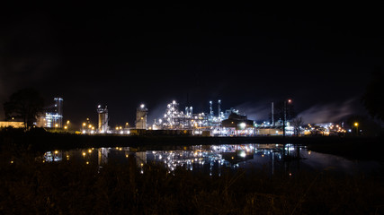 Fototapeta na wymiar Lights of petrochemical refinery at night reflecting in water. Tessenderlo, Belgium