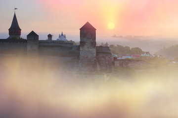 Foggy morning on the river fortress in Kamyanets-Podilsky on the background of the dawn mist gentle waves give the romantic charm of the legends of history of Ukraine in Eastern Europe.