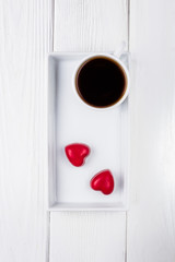 Happy Valentine's Day. Black coffee and two red chocolate hearts on a wooden background. Free space for text.