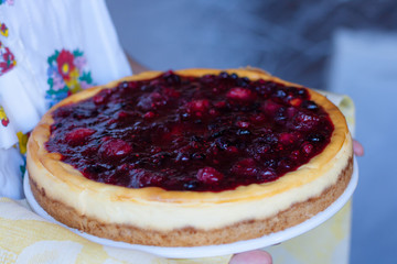 Women holding fresh from the  oven cheesecake pie. Red Berries, blueberry,strawberry...Shallow depth of field, focus on the central part of the cake.