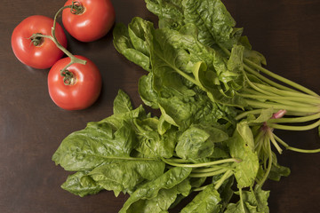 Tomatos and Spinach. Fresh organic raw produce on a kitchen table.