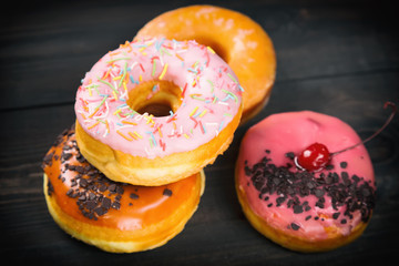 Different donuts on dark wooden background. Close up image with selective focus