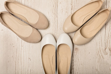 Women shoes (ballet flats) white and beige on a light wooden background.