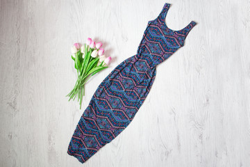 Long blue dress in an ornament, a bouquet of tulips. Fashionable concept, wooden background