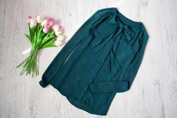 Emerald blouse, bouquet of tulips. Fashionable concept, wooden background