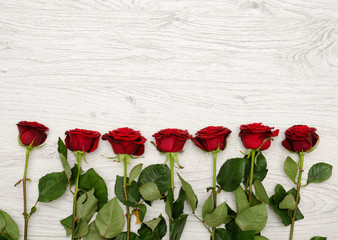 Fototapeta na wymiar Dark red rose on a light wooden background at the edge of the frame, top view. Space for text