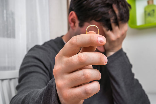 Man is holding wedding ring - divorce concept