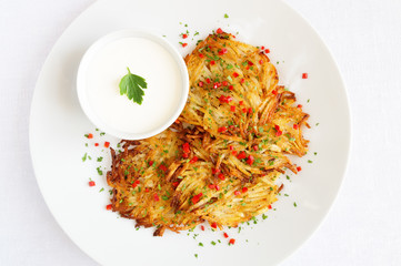 rosti ( roschti ) decorated  and sour cream decorated with parsley and chili pepper