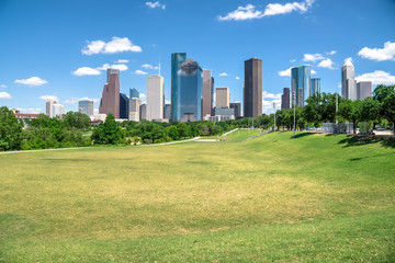 Downtown Houston at daytime with cloud blue sky. Green park lawn and modern skylines. It is the...