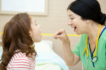 Senior woman professional pediatrician examining her young female patient