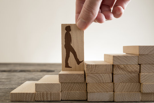 Man holding with his fingers wooden domino with shape of businessman