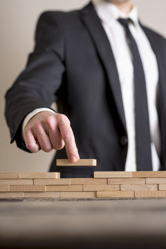 Businessman in business suit placing wooden blocks on table