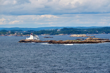 Lighthouse with residential house standing on a very small and narrow cliff in the water at the sea entry to Stavanger in Norway