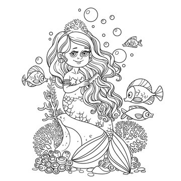 Beautiful little mermaid girl sits on a rock and combs her hair