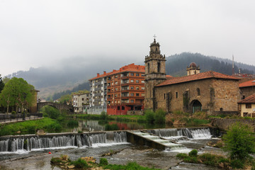 Obraz premium Church with river and waterfall in foreground of Balmaseda, Bizkaia, Basque Country, Spain
