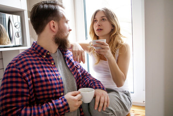 Young couple is drinking tea and coffee at home