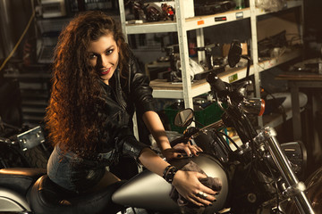 Obraz na płótnie Canvas Gorgeous young woman polishing her motorbike at the workshop