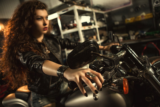 Beautiful young biker woman on her motorcycle at the workshop