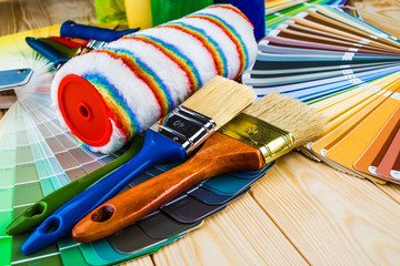 Painter and decorator work table with house project, color swatches, painting roller and paint...