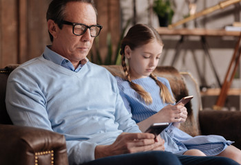 Old man and kid testing smartphones together at home