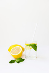 Homemade lemonade with water, lemon and mint leaves in a glass on a white background.