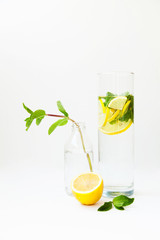 Homemade lemonade with water, lemon and mint leaves in a glass on a white background.