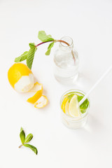 Homemade lemonade with water, lemon and mint leaves in a glass on a white background.