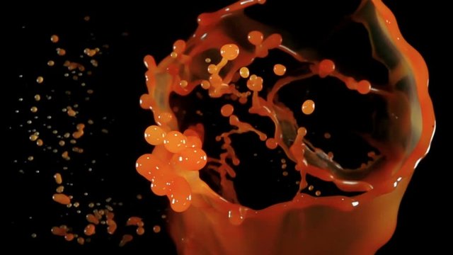 Fresh organic carrot juise bouncing against to the camera on a black background in slow motion