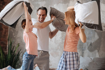 Lively family enjoying pillow fight at home