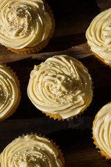 A  vertical landscape photo of five delicious cream colored cupcakes on a wooden board.  This image can also be used as a background. 