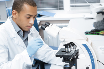 Professional male scientist working on his microscope at the lab