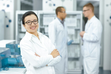 Cheerful senior female scientist posing proudly at her lab