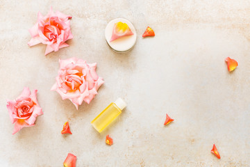 Spa setting with flowers,  rose moisturizing cream and essential oil. Spa theme. Top view, blank space, concrete background
