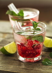 Tasty cold fresh drink lemonade with raspberry, mint, ice and lime in glass. Closeup.