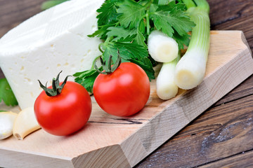 Cheese with vegetable on chopping wooden board