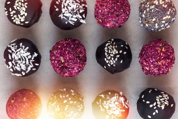 Fitness raw bites, chocolate truffles with rose petals from above. Food photography on gray background