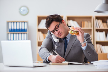 Hungry funny businessman eating junk food sandwich